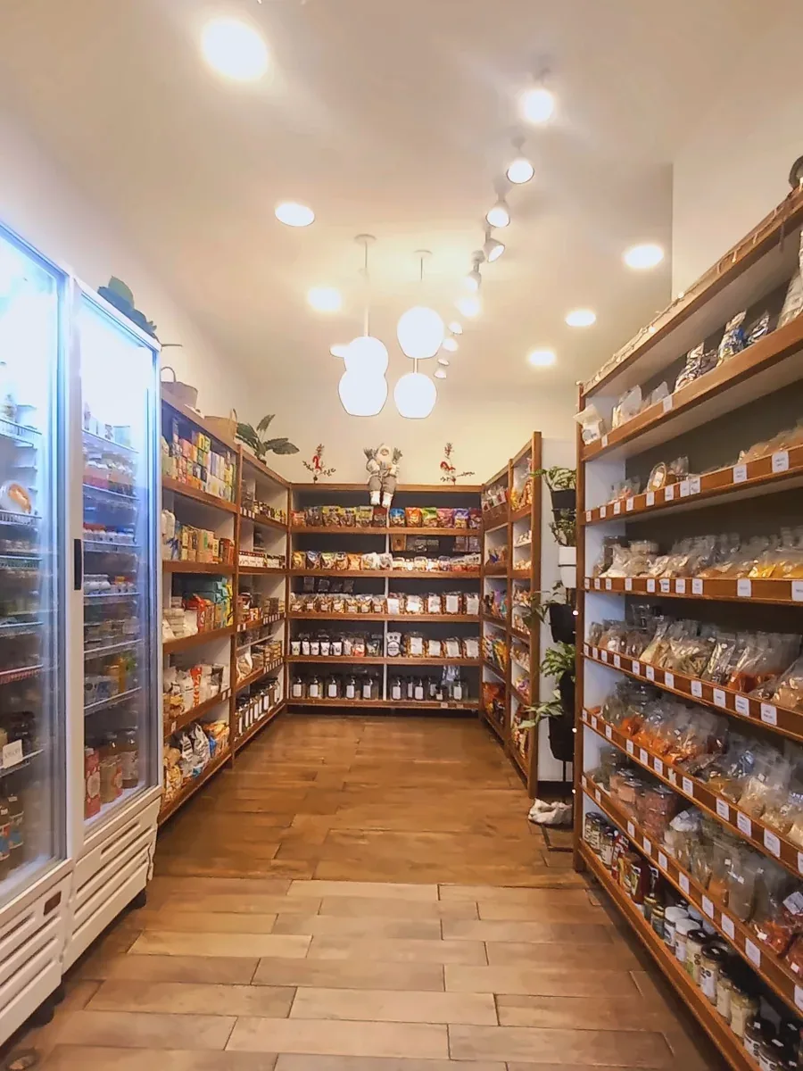 Pasillo con góndolas de madera, heladeras y lámparas colgantes