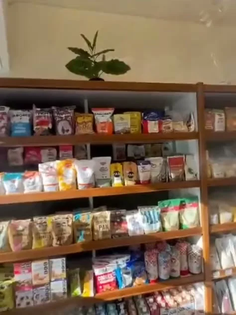 Estanterías de madera llenas de paquetes de galletitas, harinas y snacks